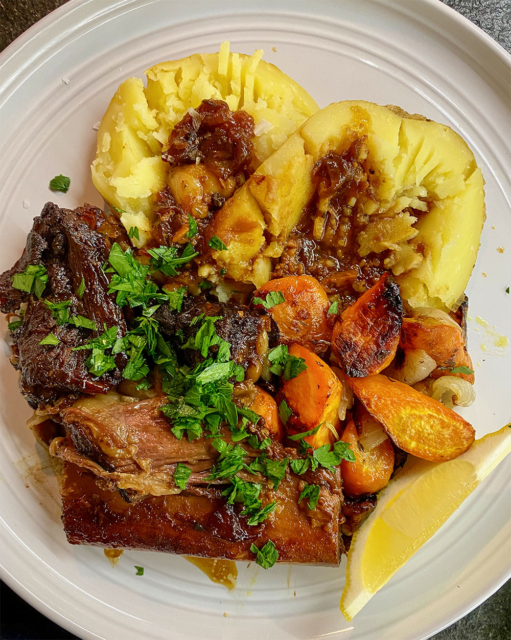 a plate of food with braised meat and potatoes