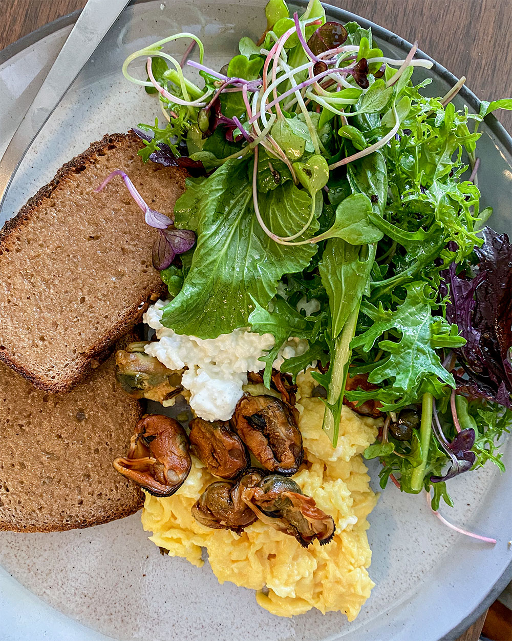 plate of food with salad, toast, eggs, and mussels