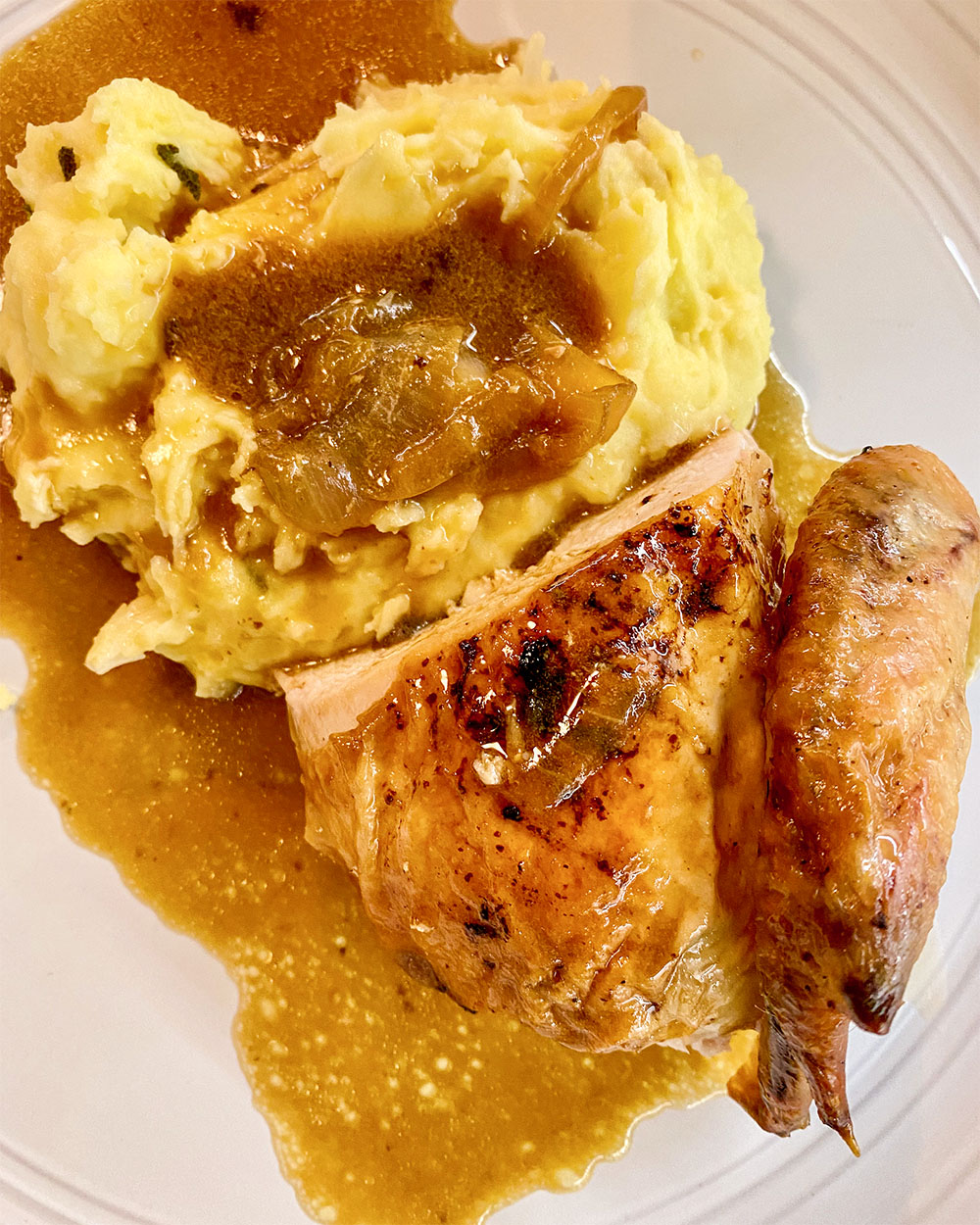 a plate of food with mashed potatos, chicken, and gravy